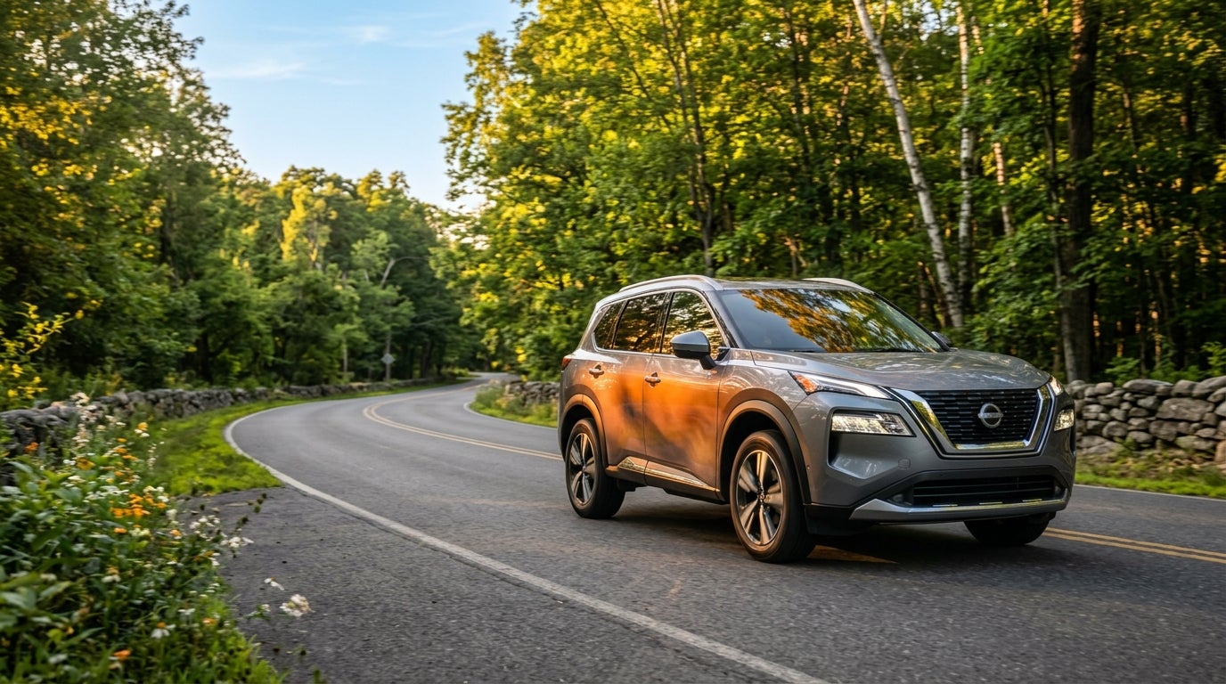A silver Nissan SUV drives along a winding road surrounded by lush green forests during golden hour. (Representative image for illustration purposes only. Actual vehicle may vary based on trim and configuration.)