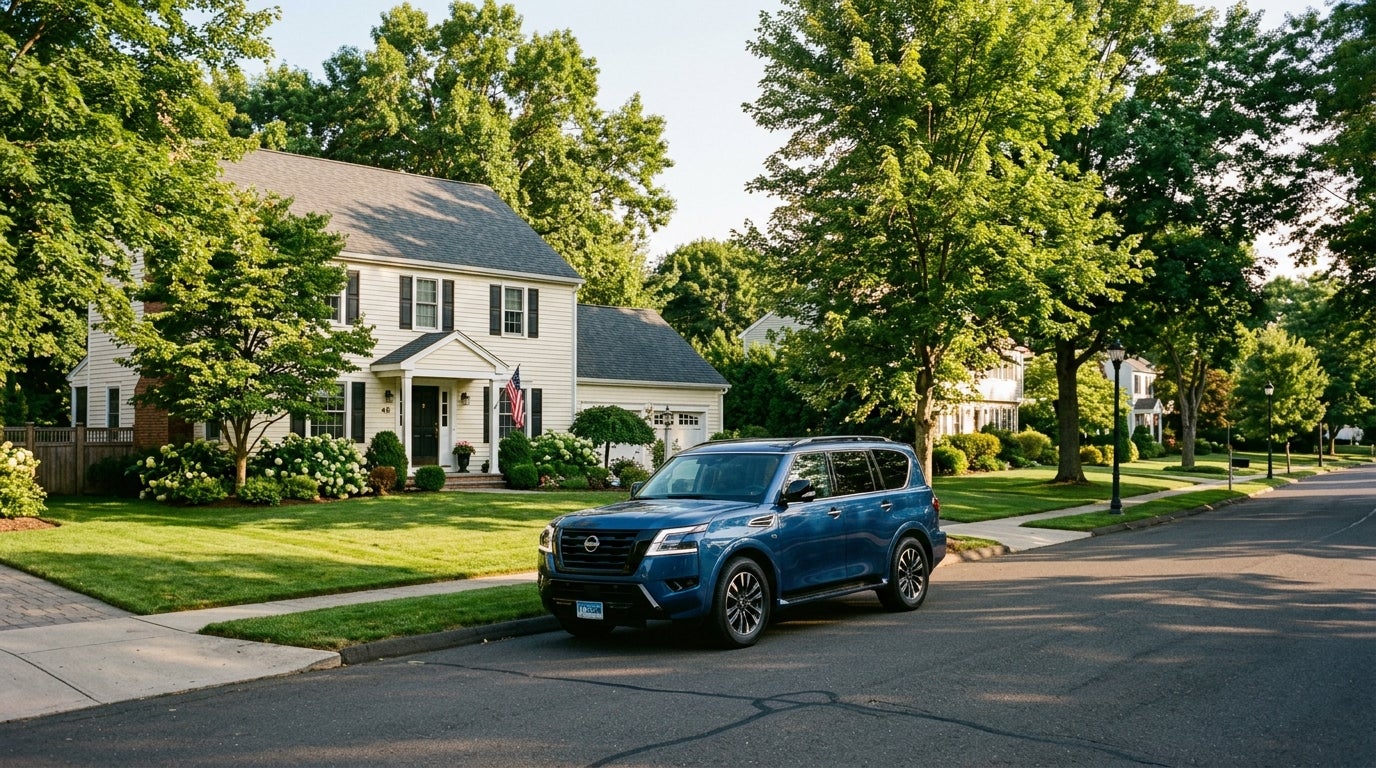 Blue Nissan SUV parked on a quiet suburban street in front of a colonial-style house with a manicured lawn. (Representative image for illustration purposes only. Actual vehicle may vary based on trim and configuration.)
