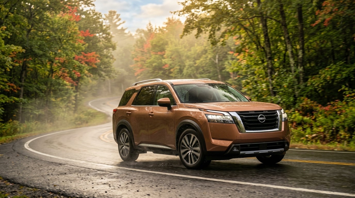 A copper Nissan SUV driving along a wet, winding forest road surrounded by autumn trees. (Representative image for illustration purposes only. Actual vehicle may vary based on trim and configuration.)