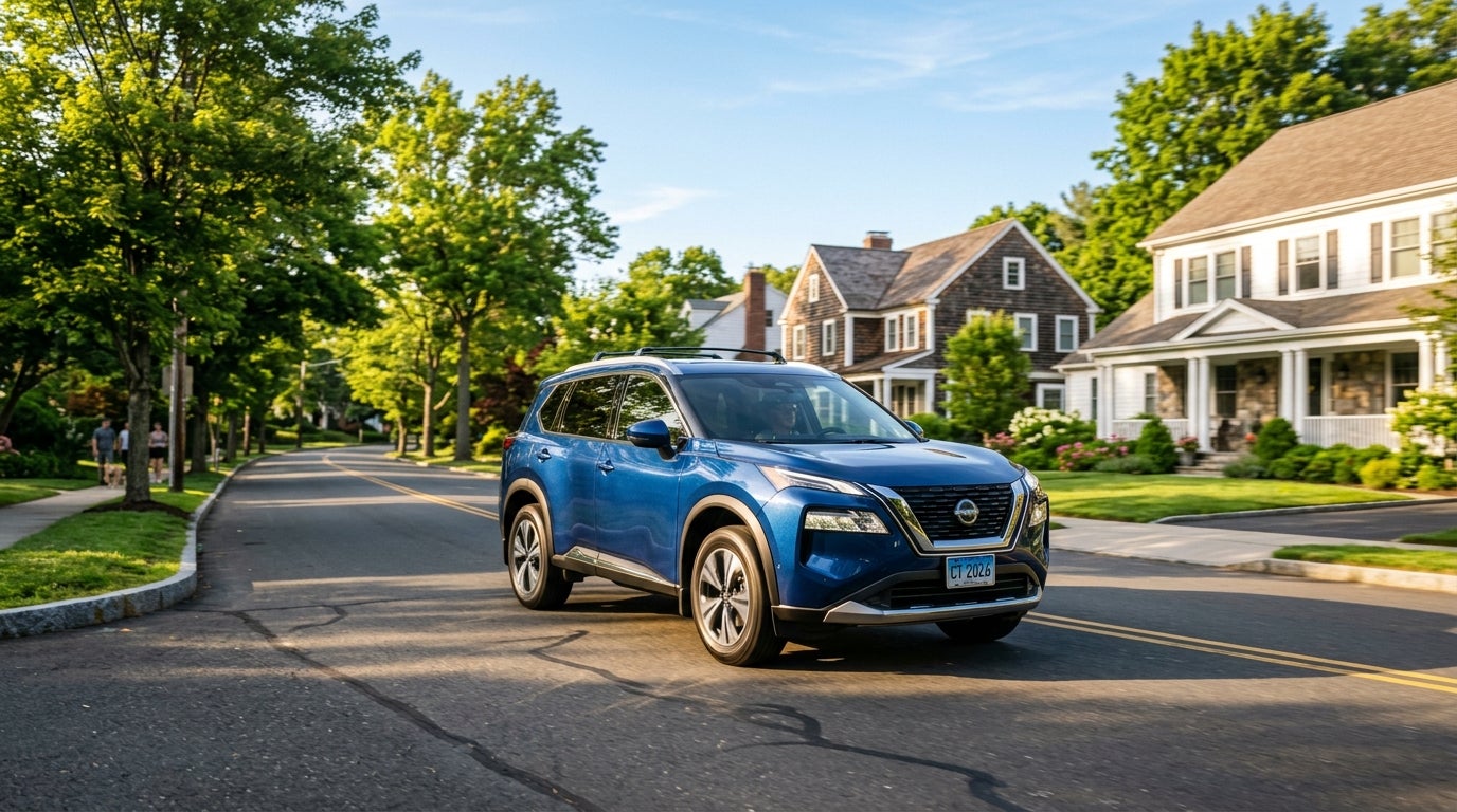 A blue Nissan Rogue SUV driving down a tree-lined residential suburban street past houses. (Representative image for illustration purposes only. Actual vehicle may vary based on trim and configuration.)