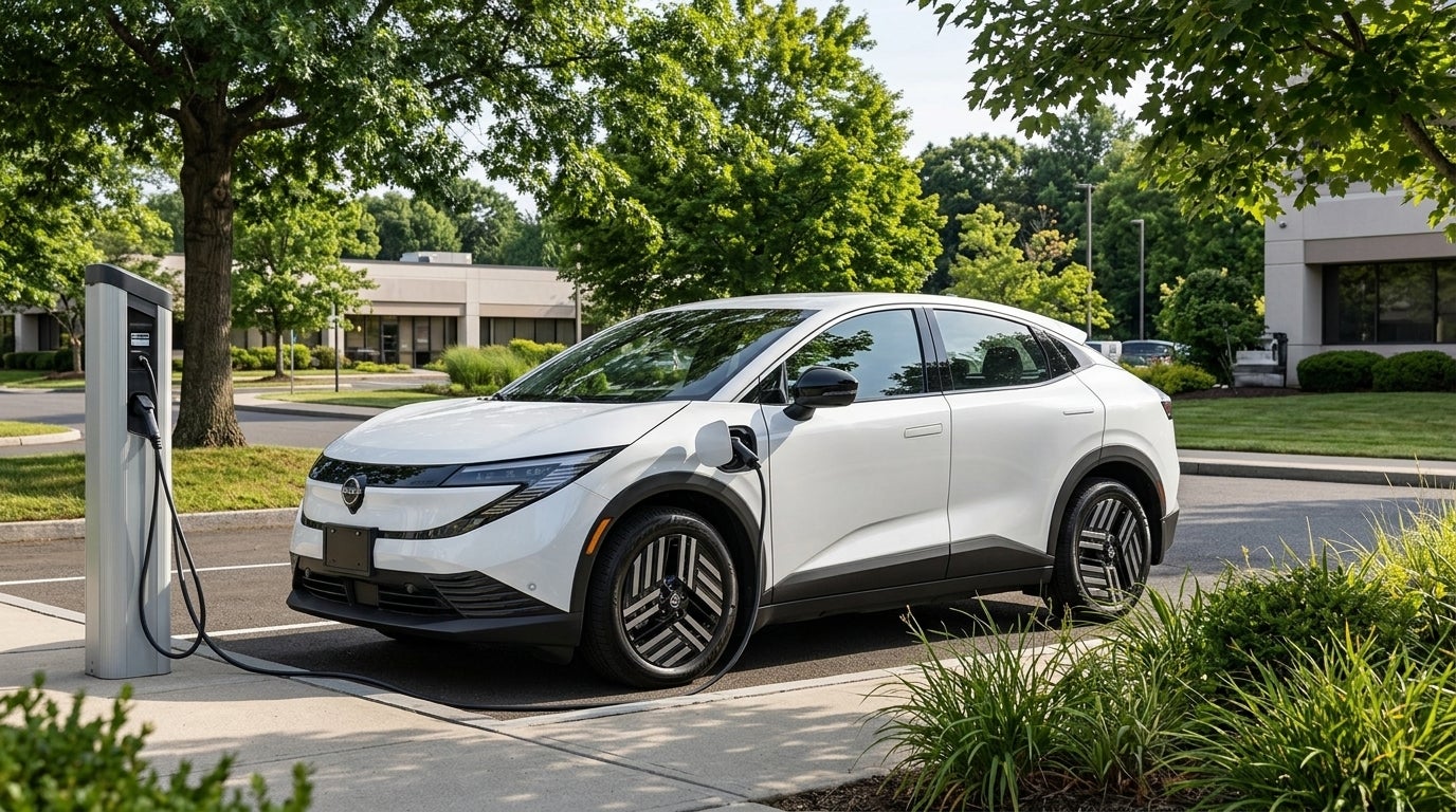 White Nissan Ariya electric SUV parked outdoors and plugged into an EV charging station. (Representative image for illustration purposes only. Actual vehicle may vary based on trim and configuration.)
