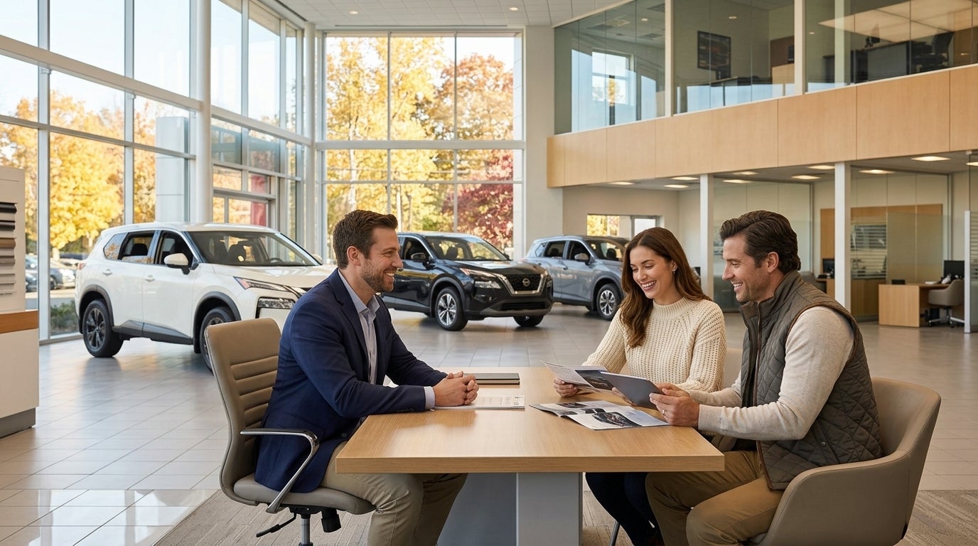 A couple sits at a desk talking with a salesman in a bright car dealership showroom filled with SUVs. (Representative image for illustration purposes only. Actual vehicle may vary based on trim and configuration.)