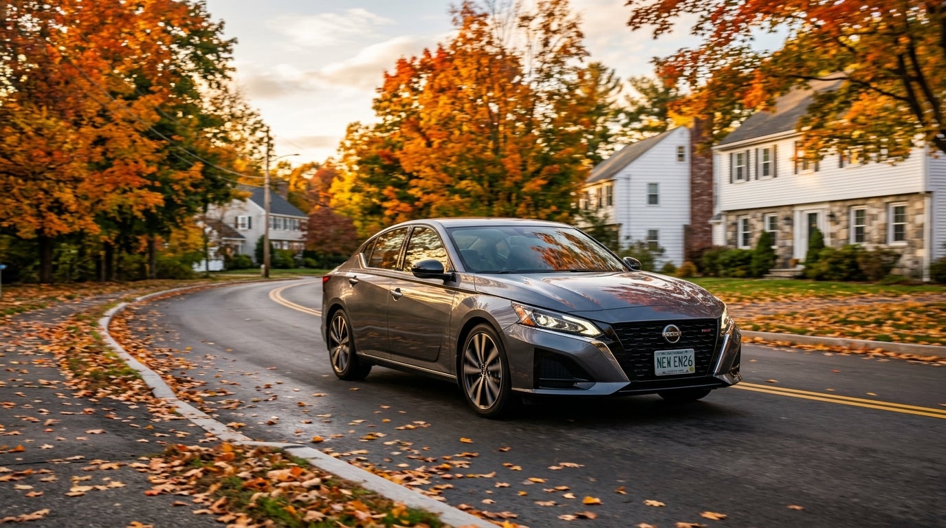A grey Nissan Altima sedan driving down a residential street surrounded by colorful autumn trees and fallen leaves. (Representative image for illustration purposes only. Actual vehicle may vary based on trim and configuration.)